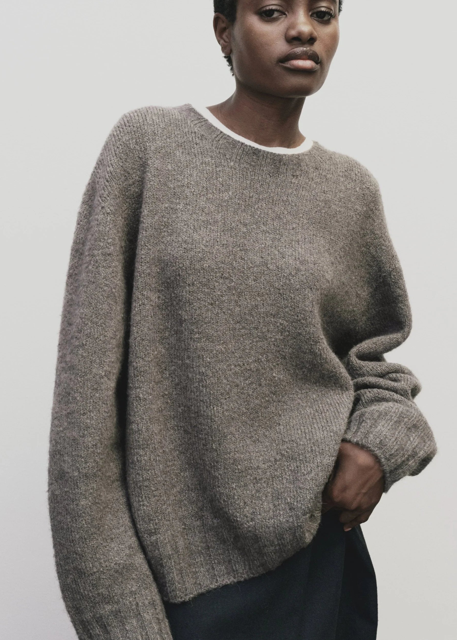 Person wearing a gray sweater against a plain background