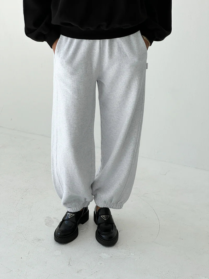 Person wearing gray sweatpants and black shoes on a white background