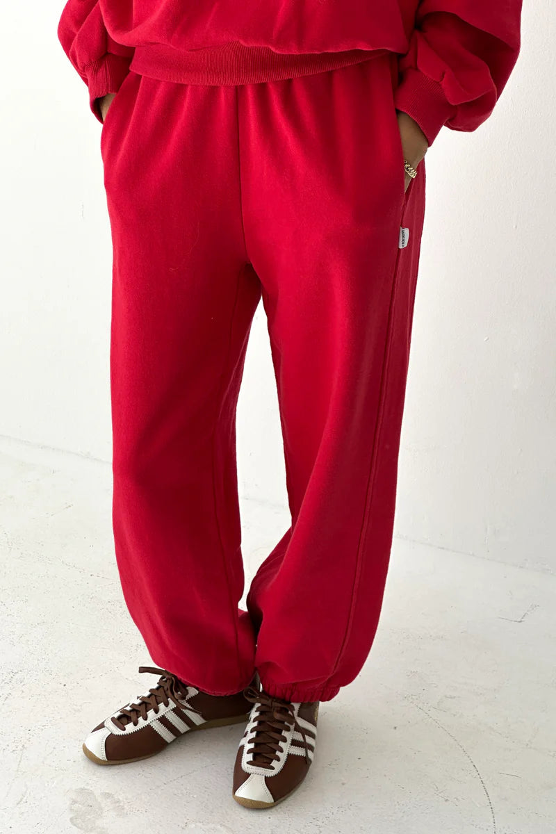 Person wearing a red tracksuit with brown shoes on a white background