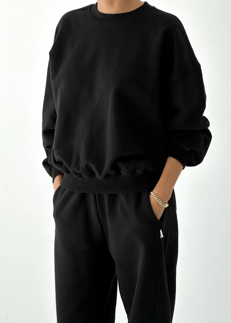 Person wearing a black sweatshirt and pants on a white background