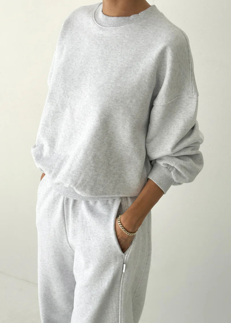 Person wearing a gray tracksuit against a plain background