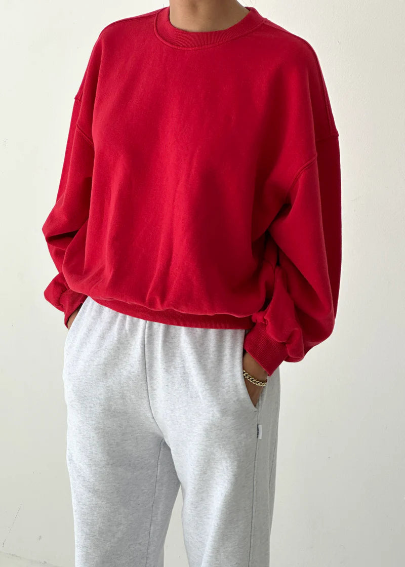 Person wearing a red sweatshirt and gray pants on a white background
