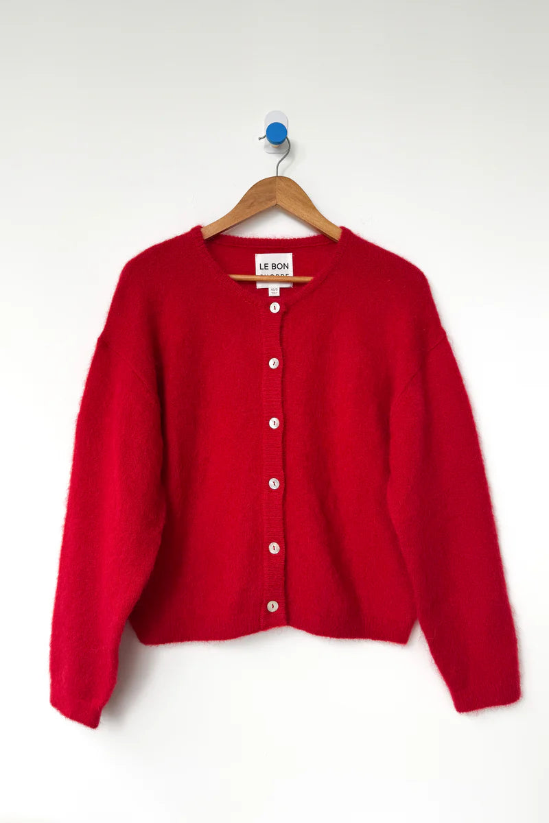Red cardigan on a hanger against a white background